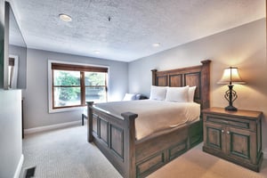 Guest bedroom with striking solid wood bedframe, queen bed and twin bed with large picture window