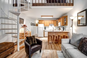 Relax in your spacious openconcept living area featuring a fully equipped kitchen, comfortable seating, and charming spiral staircase to the loft above.