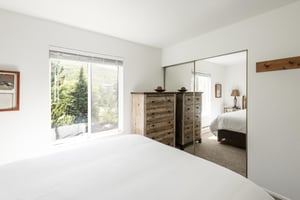 Main bedroom with mirrored bypass closet doors and coat rack