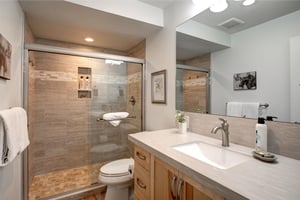 Indulge in your beautifully appointed bathroom featuring a spacious walkin shower, elegant stone tilework, and modern vanity with ample storage for all your essentials.