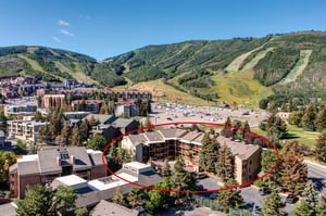 Aerial view of the property complex nestled in a mountain valley with ski slopes and resort town surroundings.