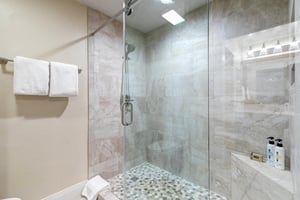 Step into your private spalike shower, where soft rainfall and smooth pebble flooring invite you to unwind. Fresh towels and premium amenities are ready for your refreshing escape.