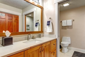 Fresh linens await in this bright bathroom with warm wood tones, a spacious vanity, and modern fixtures—all ready for your arrival.