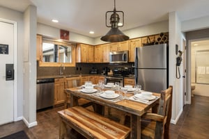 Fully equipped kitchen with wood cabinetry, stainless steel appliances and dining table that seats 6 people