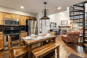 Open kitchen and dining area with wood cabinetry, stainless appliances and rustic dining table with seating for 6