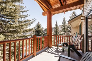 Private covered patio with rustic wood railing and peaceful views of the surrounding evergreen trees