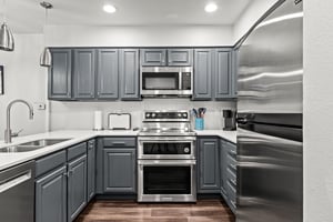 Fully equipped kitchen with blue cabinetry, quartz counters and stainless steel appliances