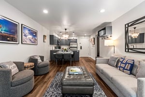 Spacious openconcept living room with sofa, lounge chairs, dining area and modern kitchen beyond
