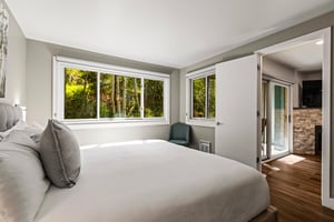 Bright king bedroom with large windows overlooking a peaceful grove of aspen trees