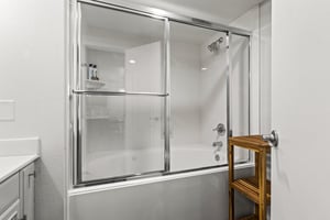 Guest bathroom tub and shower combination with sliding glass doors