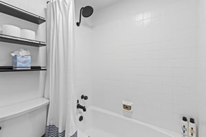 The bathtub and shower combination with crisp white surround and black hardware.