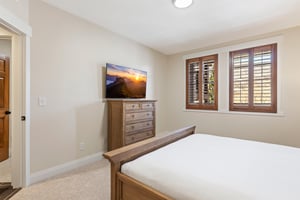 Second main bedroom with king bed, wood dresser, TV and windows with wood shutters for added privacy.
