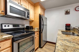 Full kitchen with wood cabinetry and black and stainless steel appliances.