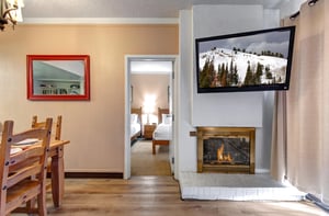 Cozy living area with gas fireplace, wallmounted TV and open doorway leading into the bedroom.