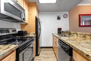 Galleystyle kitchen with wood cabinetry and black and stainless steel appliances.