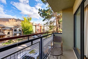Private balcony overlooking the surrounding neighborhood with scenic mountain views in the distance with seating.