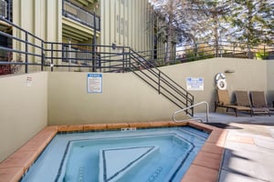 Community outdoor hot tub with surrounding deck and convenient access from the condominium building.