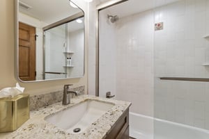 The bathroom with a bathtub and shower combination and single sink vanity.