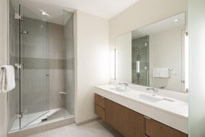 Ensuite guest bathroom, tiled shower with glass door and dual vanity.