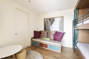 Fun lounge sofa in the bunk bedroom with colorful throw pillows, mountain inspired wall art, and round play table.
