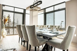 Bright dining area with seating for eight, modern chandelier and floortoceiling windows with mountain views.