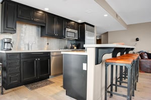 Modern kitchen with dark wood cabinetry, stainless steel appliances, stone countertops and breakfast bar seating.