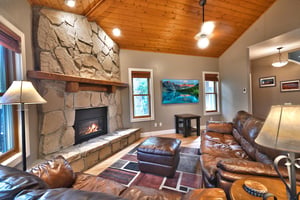 Living room with feature rock fireplace wall, leather couches and wall mounted flat screen TV.