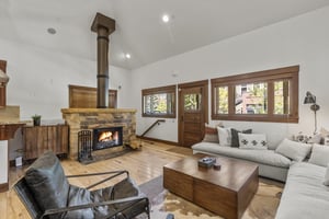 The living room features a wood burning fireplace with stone surround and a sectional sofa with stylish cozy throw pillows.