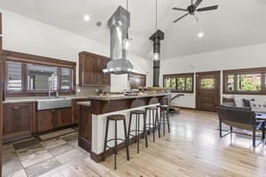 The breakfast bar with four barstools overlooks the kitchen with beautiful wood cabinets and window over the sink.