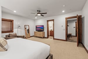 The spacious main suite has a floor mirror, dresser, and flat screen TV.