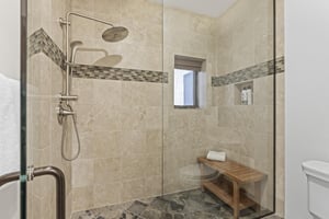 The main suite has a walk in shower with European glass door and wooden bench.