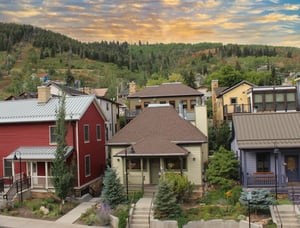 The exterior of Park Villa has a charming front porch, steps down to the sidewalk, and mountains and forest behind it.