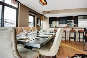 Dining area with stonetop table, upholstered seating and open views into the modern kitchen and breakfast bar.