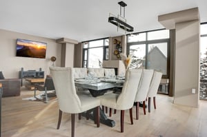 Bright dining area with seating for eight, modern chandelier and floortoceiling windows with mountain views.