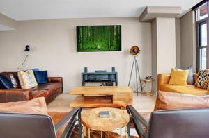 Cozy living room with leather seating, wood coffee tables, wallmounted TV and modern mountain decor.