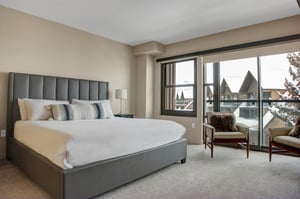 Bright king bedroom with sitting area and large windows offering mountain views.
