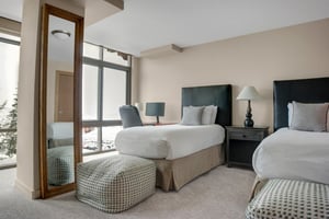 Bedroom with two beds, bedside table and large windows offering mountain views.