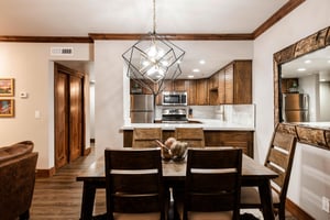 Dining area with seating for six, modern chandelier and open access to the renovated kitchen.