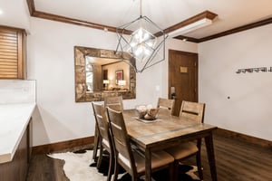 Rustic dining area with seating for six, statement chandelier and large wall mirror.