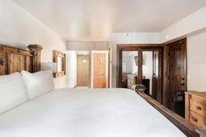 Spacious bedroom with rustic wood bed, wardrobe, dresser and warm wood accents.