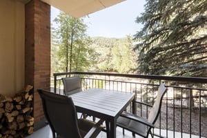 Private furnished patio with outdoor dining table and scenic mountain and tree views.