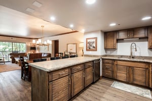 Spacious kitchen with granite peninsula, wood cabinetry and open layout connecting to the dining area.