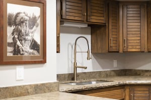 Kitchen sink with granite countertop, modern faucet, tile backsplash and wood cabinetry.