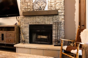 Rustic stone fireplace with raised hearth and wood mantel in the living room.
