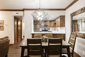 Unit 227 dining area with seating for five, statement chandelier and open kitchen in the background.