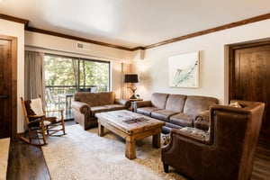 Unit 229 living room with leather seating, wood coffee table and sliding doors opening to the balcony.