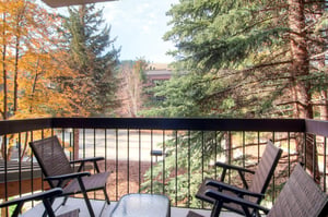 Unit 227 private balcony with outdoor seating and peaceful views of surrounding trees.
