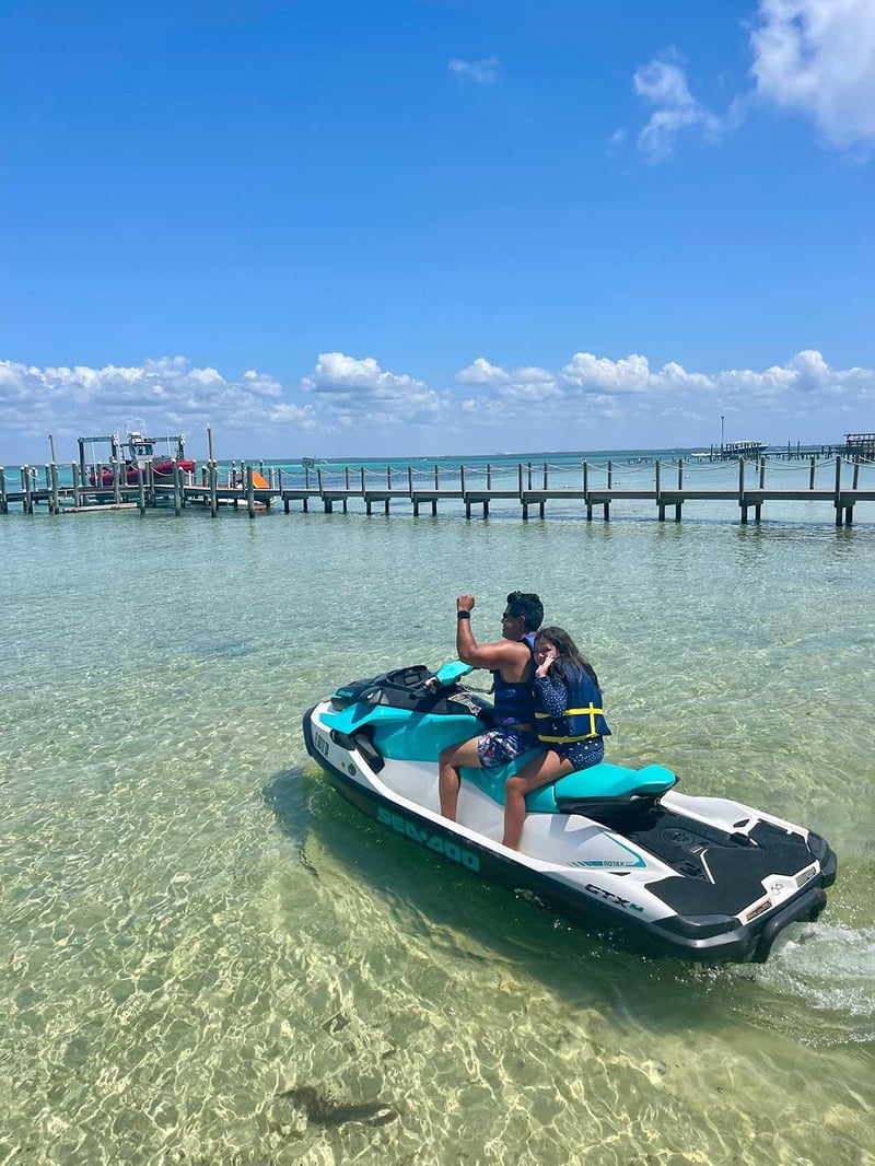 Family riding jet ski in shallow clear water near Crab Island and dock in Fort Walton Beach