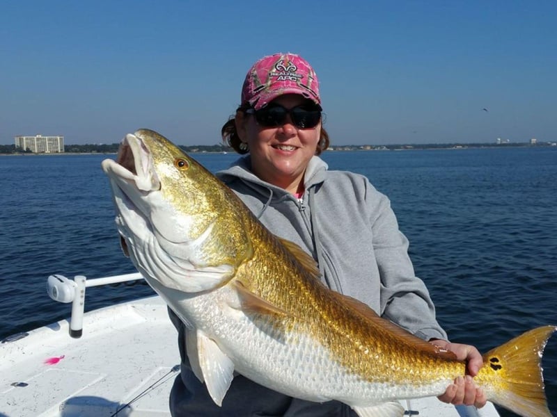 An angler showing off her catch on the boat