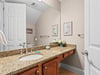 Half bathroom featuring granite countertops, warm wood cabinetry, and thoughtful coastal artwork that creates a serene atmosphere for your daily routine.